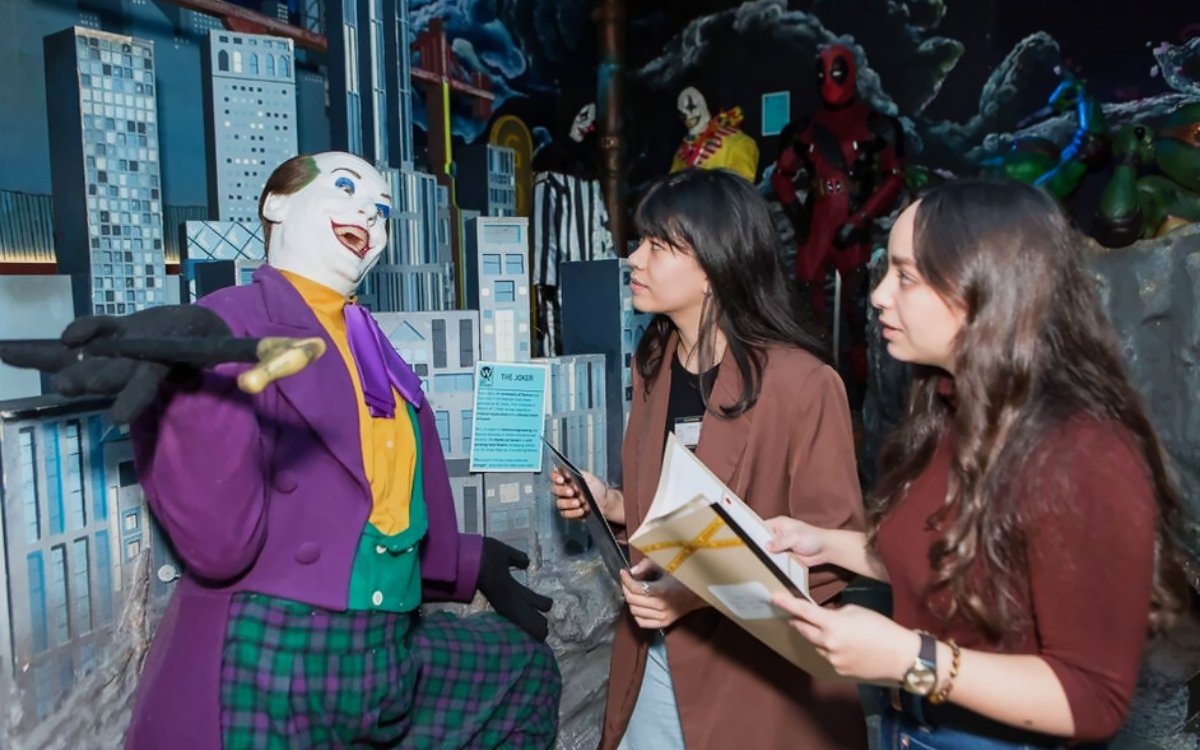 Visitors engaging with a Joker wax figure at the National Wax Museum Plus murder mystery event.