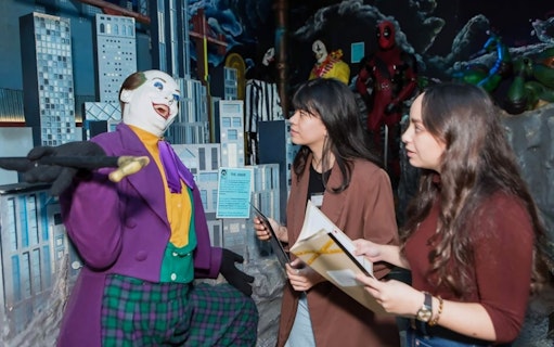 Visitors engaging with a Joker wax figure at the National Wax Museum Plus murder mystery event.