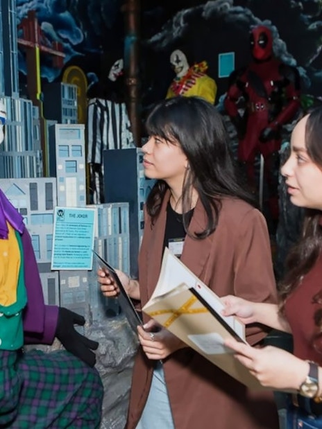 Visitors engaging with a Joker wax figure at the National Wax Museum Plus murder mystery event.