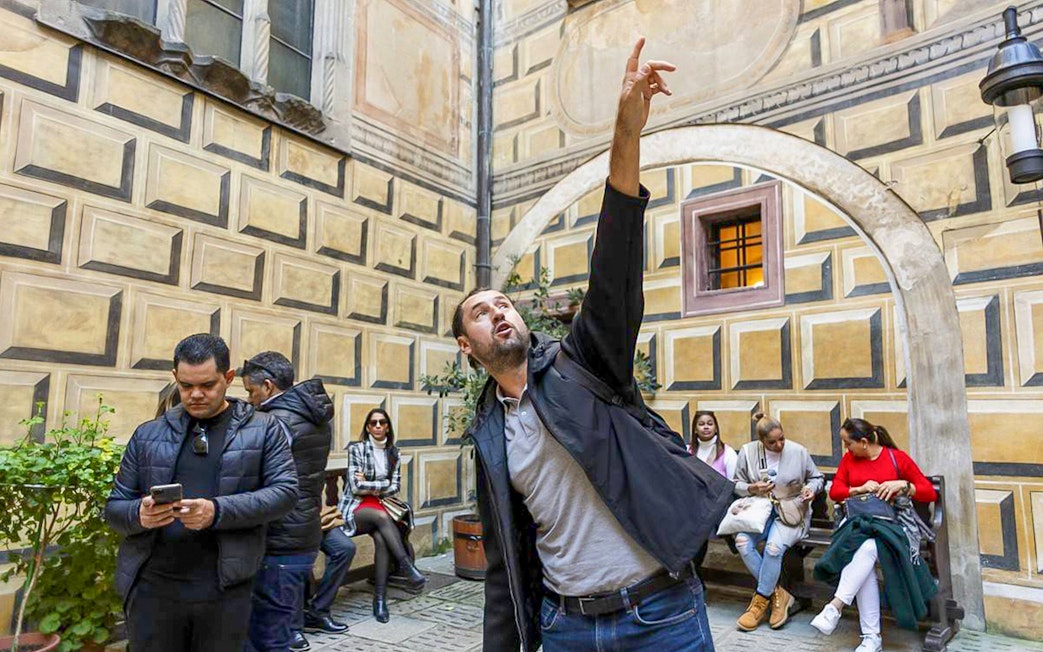 Tour guide pointing out architectural details in Cesky Krumlov courtyard.