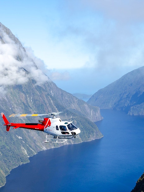 Helicopter flying over cloud-covered fiords in Milford Sound, New Zealand.