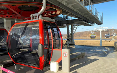 Cable car station at DMZ Tour with JSA Photo Zone, featuring red gondola and distant landscape.