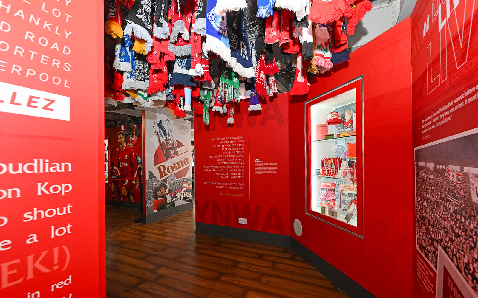 Liverpool FC stadium tour exhibit with scarves and memorabilia display.