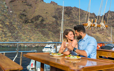 Couple dining on a boat near volcanic islands with scenic views.