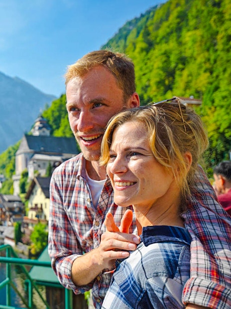 Couple enjoying the view of Hallstatt village and lake in Austria.