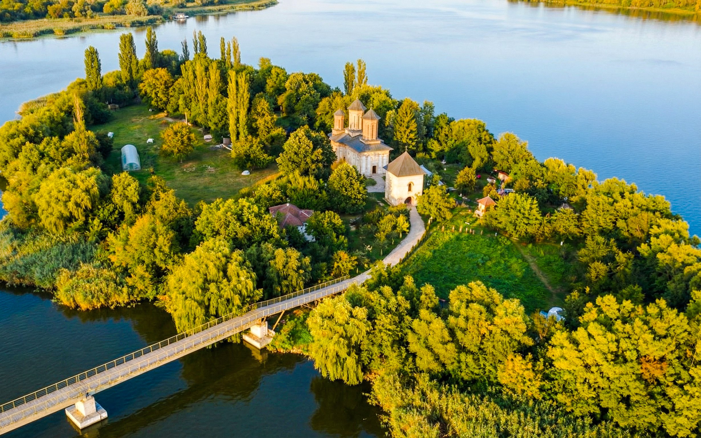 Aerial view of Snagov Monastery surrounded by lush greenery and lake in Romania.
