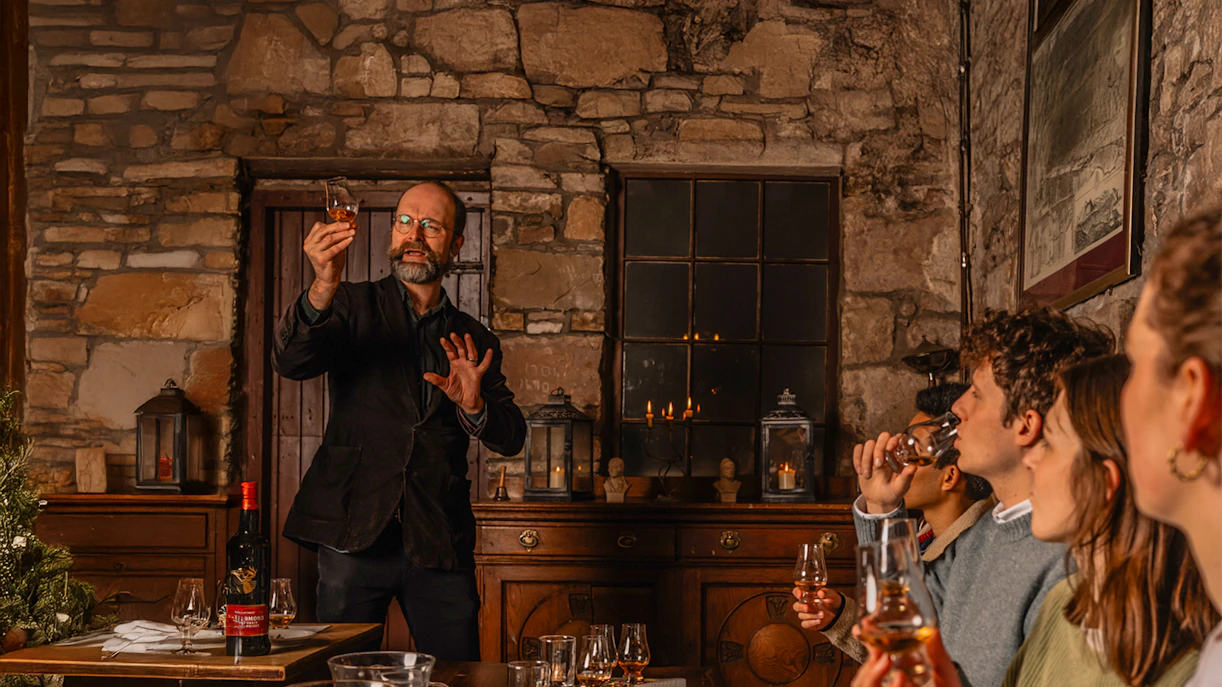 Guide leading guests in Edinburgh Whiskey Tasting Tour, showcasing whiskey samples and historic underground setting.