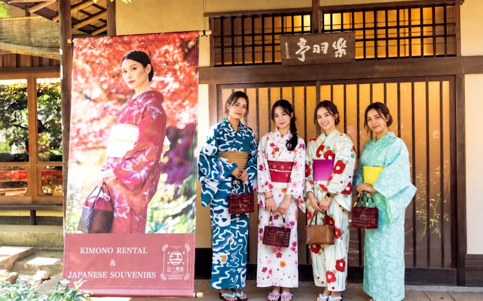 Kimono rental display with four women in kimonos at Shinjuku Gyoen National Garden, Tokyo.
