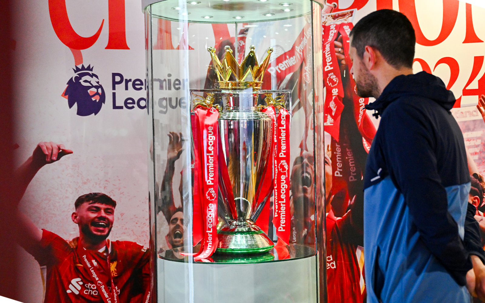 Premier League trophy display at Anfield Experience with guest observing.