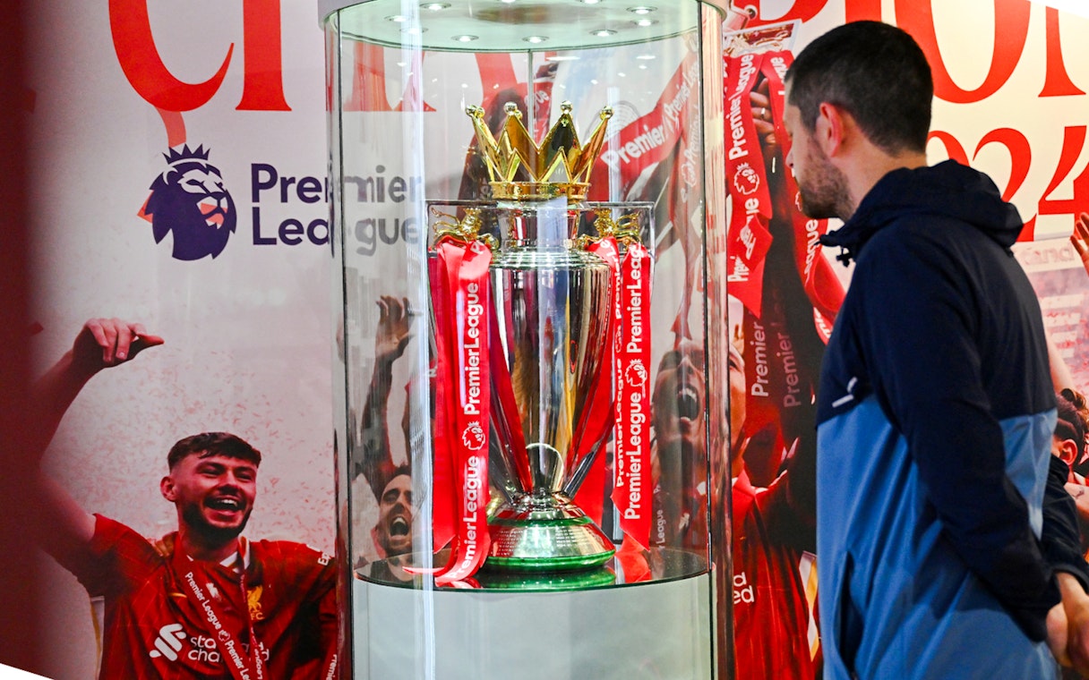Premier League trophy display at Anfield Experience with guest observing.