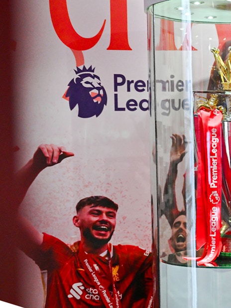 Premier League trophy display at Anfield Experience with guest observing.