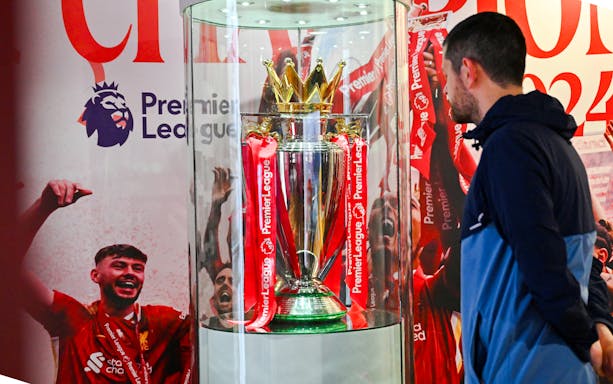Premier League trophy display at Anfield Experience with guest observing.