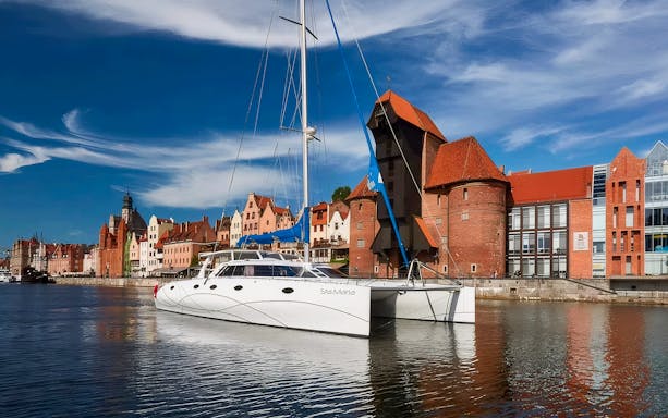 Catamaran docked in Sopot with historic waterfront buildings in the background.