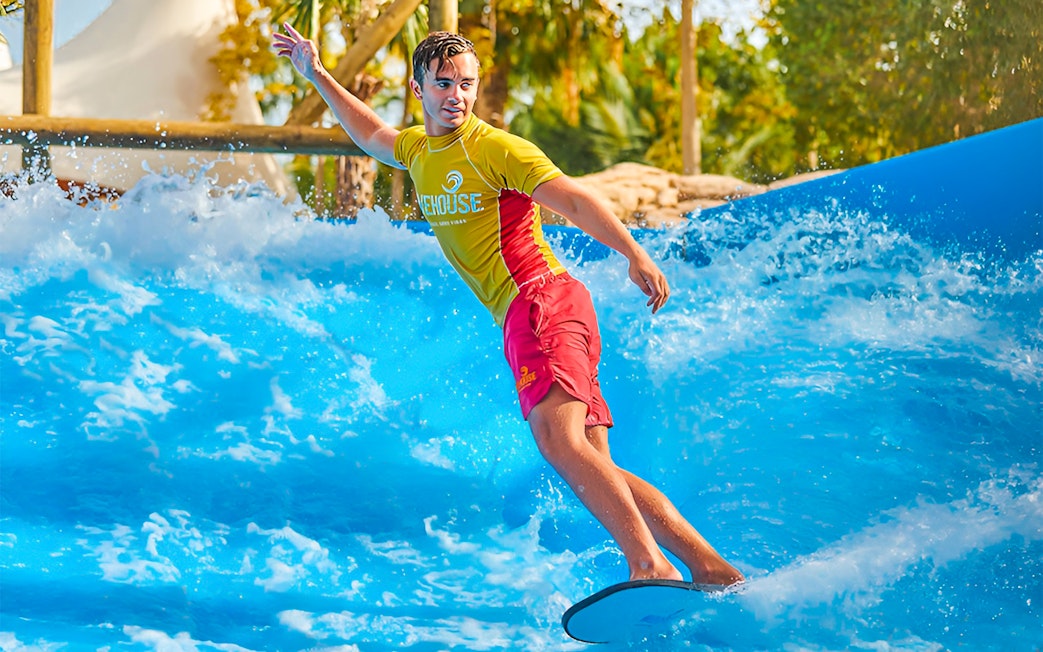 Surfer riding wave at Aquaventure Waterpark, Dubai.