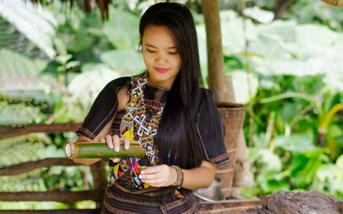 Woman in traditional attire demonstrating bamboo craft at Mari Mari Cultural Village.