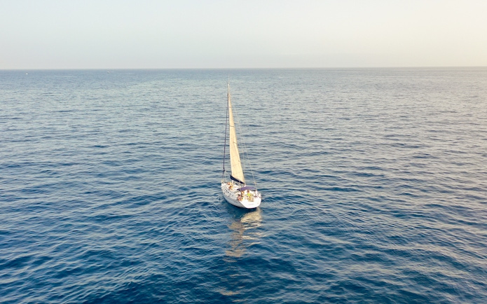 Sailboat cruising on open ocean for whale and dolphin watching tour.