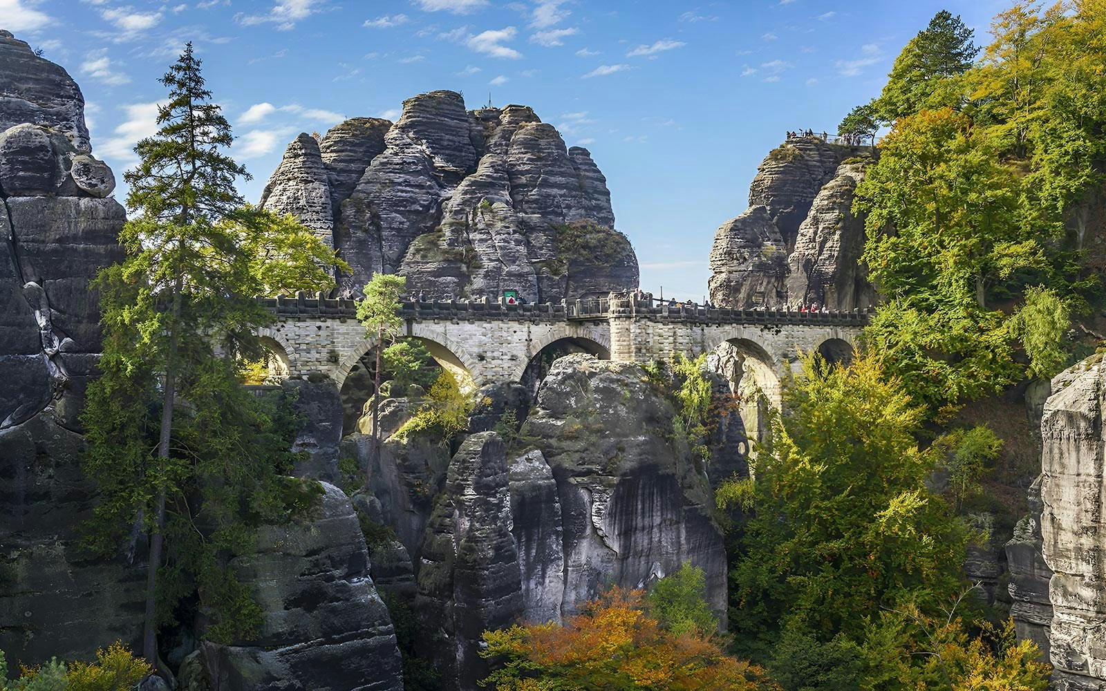 Bastei Bridge in Saxon Switzerland surrounded by rock formations and autumn trees.