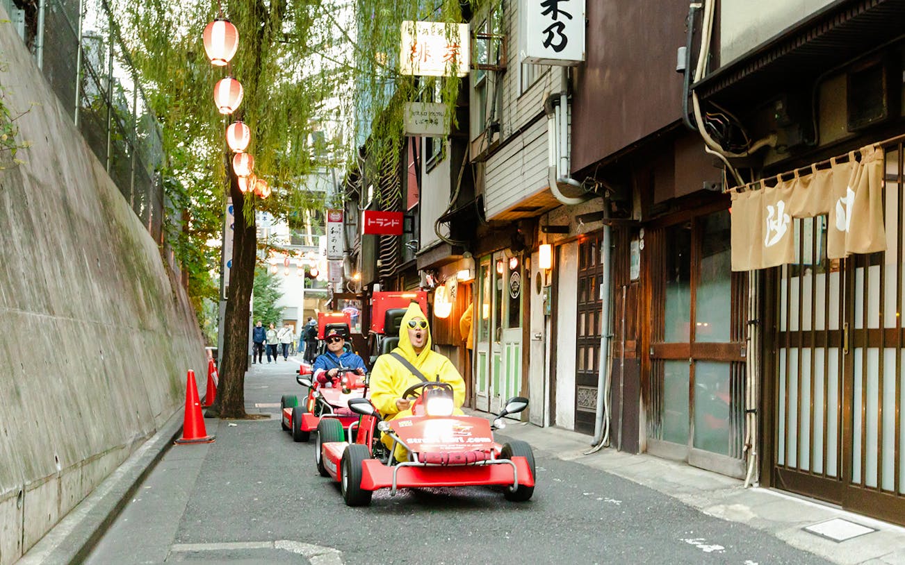 Tourists driving go karts on Shibuya streets during Tokyo go karting experience.
