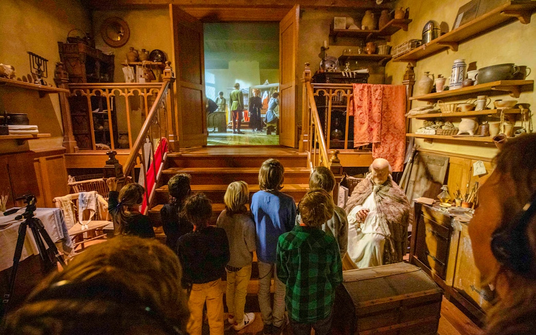 Guests watching a historical reenactment at Historium Bruges, featuring medieval decor and artifacts.