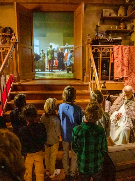 Guests watching a historical reenactment at Historium Bruges, featuring medieval decor and artifacts.