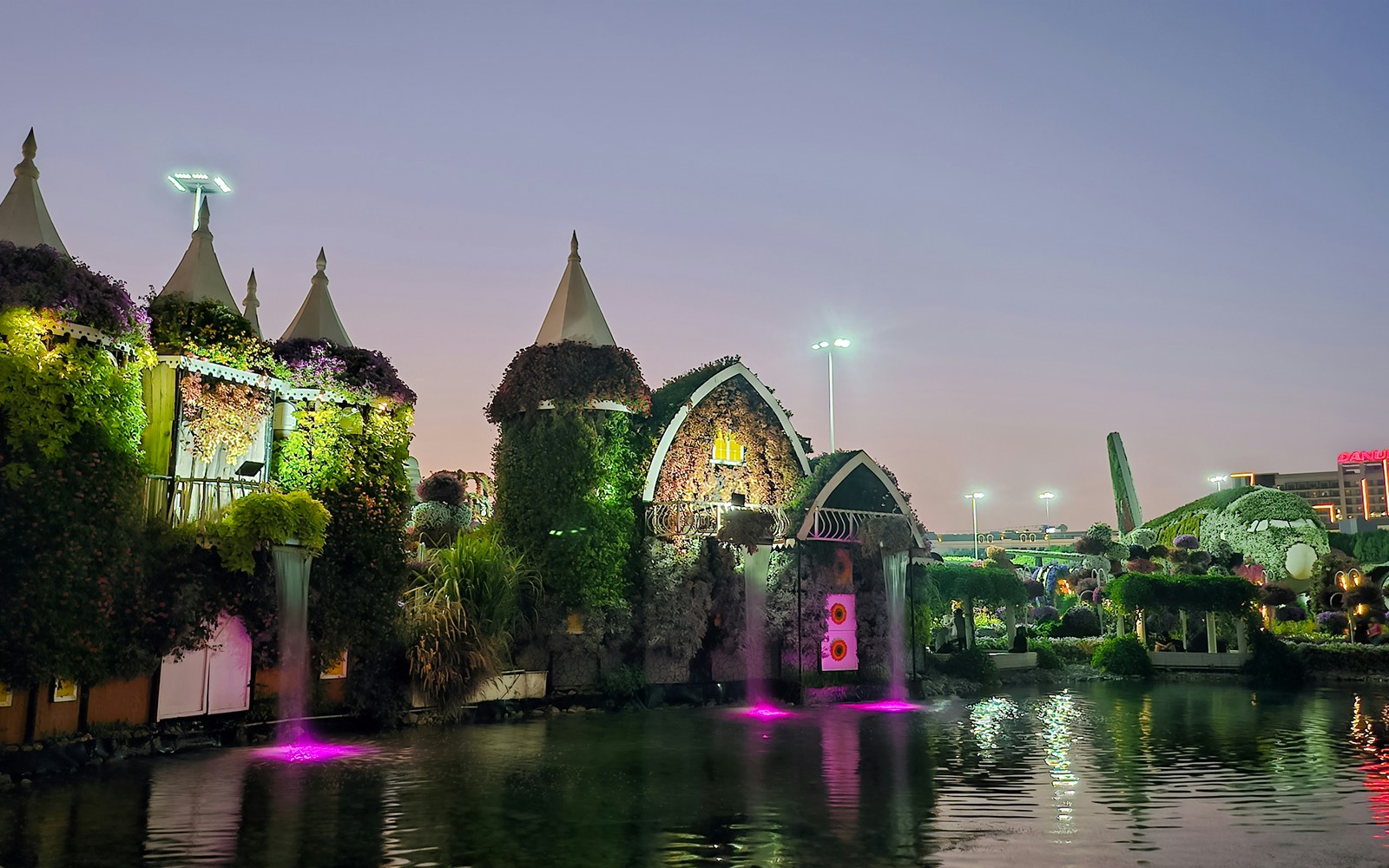 Dubai Miracle Garden floral structures and illuminated water features at dusk.