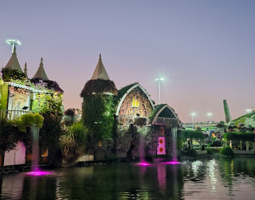 Dubai Miracle Garden floral structures and illuminated water features at dusk.