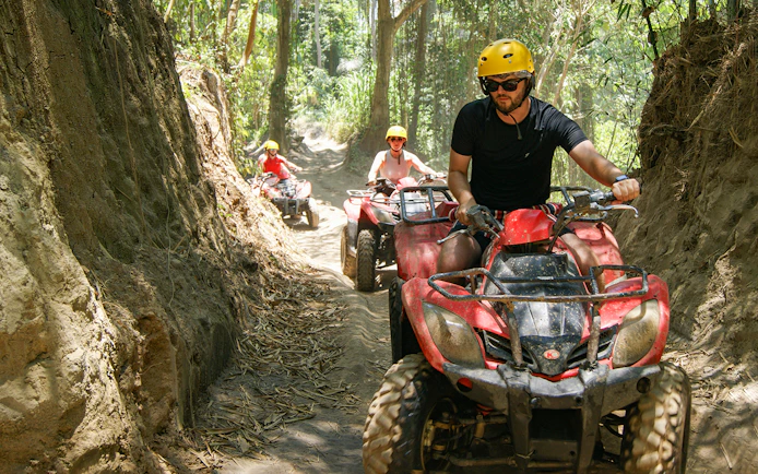 ATV riders navigating a forest trail in Bali during a guided tour.