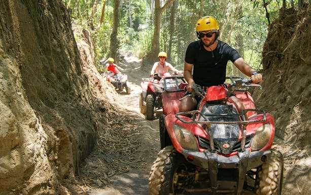 ATV riders navigating a forest trail in Bali during a guided tour.