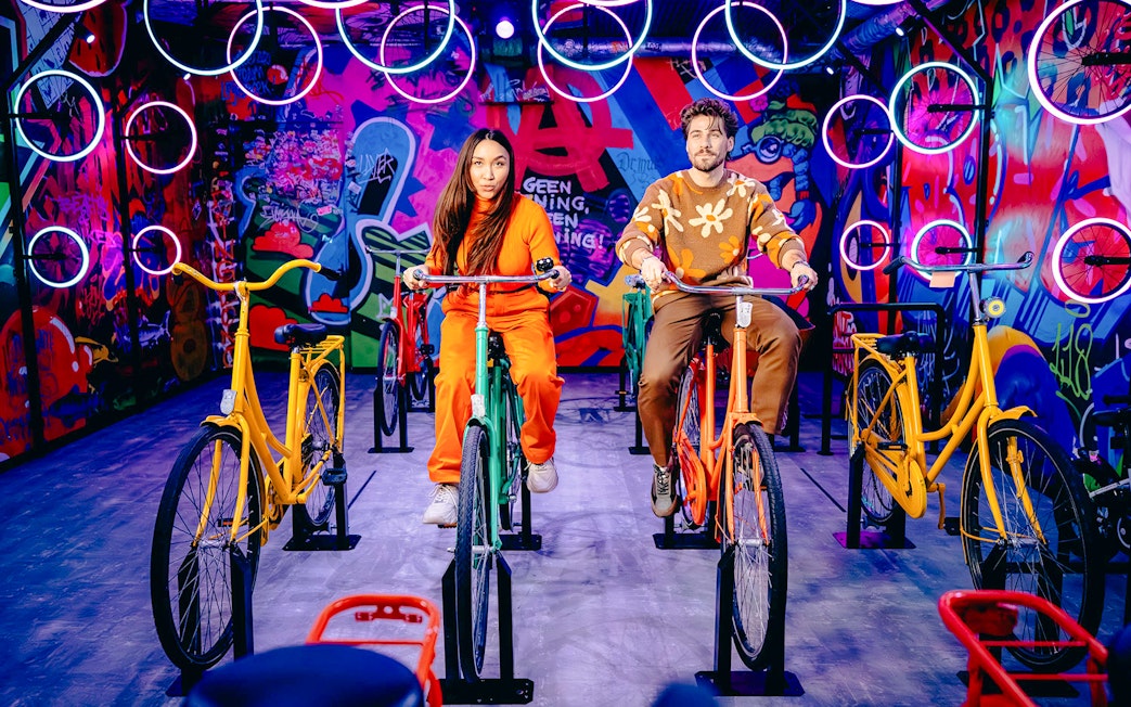Guests cycling indoors with vibrant graffiti in Highlights of Holland experience.