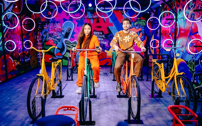 Guests cycling indoors with vibrant graffiti in Highlights of Holland experience.