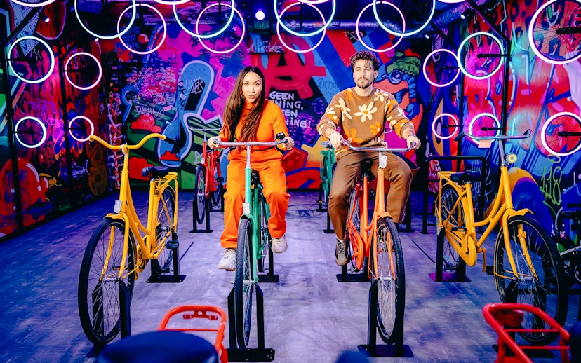 Guests cycling indoors with vibrant graffiti in Highlights of Holland experience.