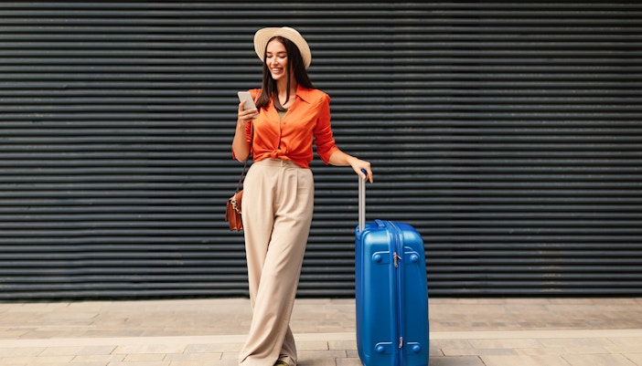 travelling woman with luggage using her phone