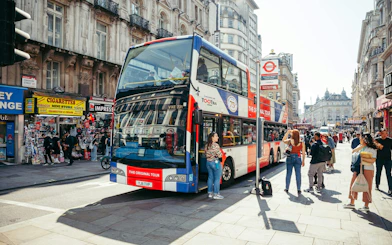 Hop-on hop-off bus at a busy London street near Coventry Street.