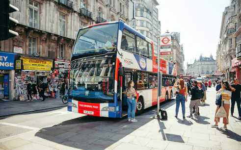 Hop-on hop-off bus at a busy London street near Coventry Street.