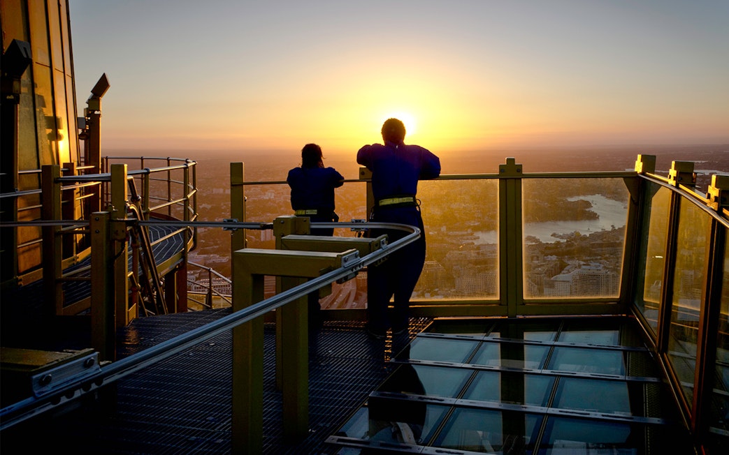 Visitors on Skywalk at Sydney Tower Eye enjoying city view at sunset.