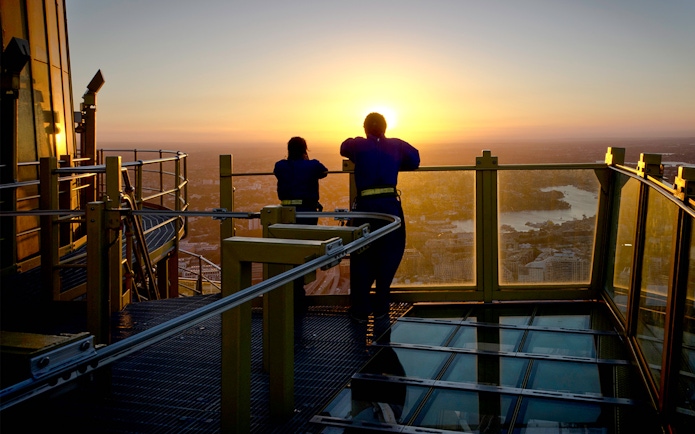 Visitors on Skywalk at Sydney Tower Eye enjoying city view at sunset.