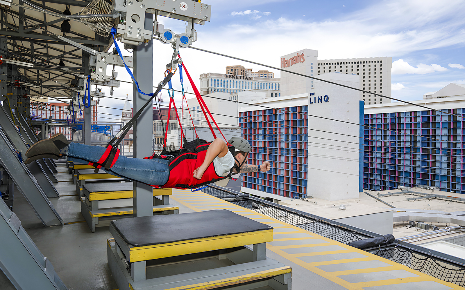 Person on Fly LINQ Zipline above Las Vegas with city buildings in background.