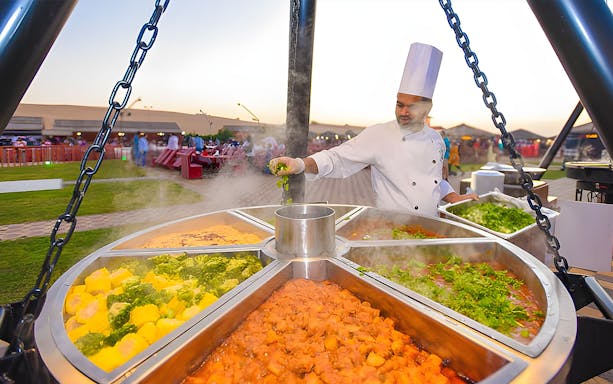 Chef preparing buffet dishes at a Premium Evening Desert Safari.