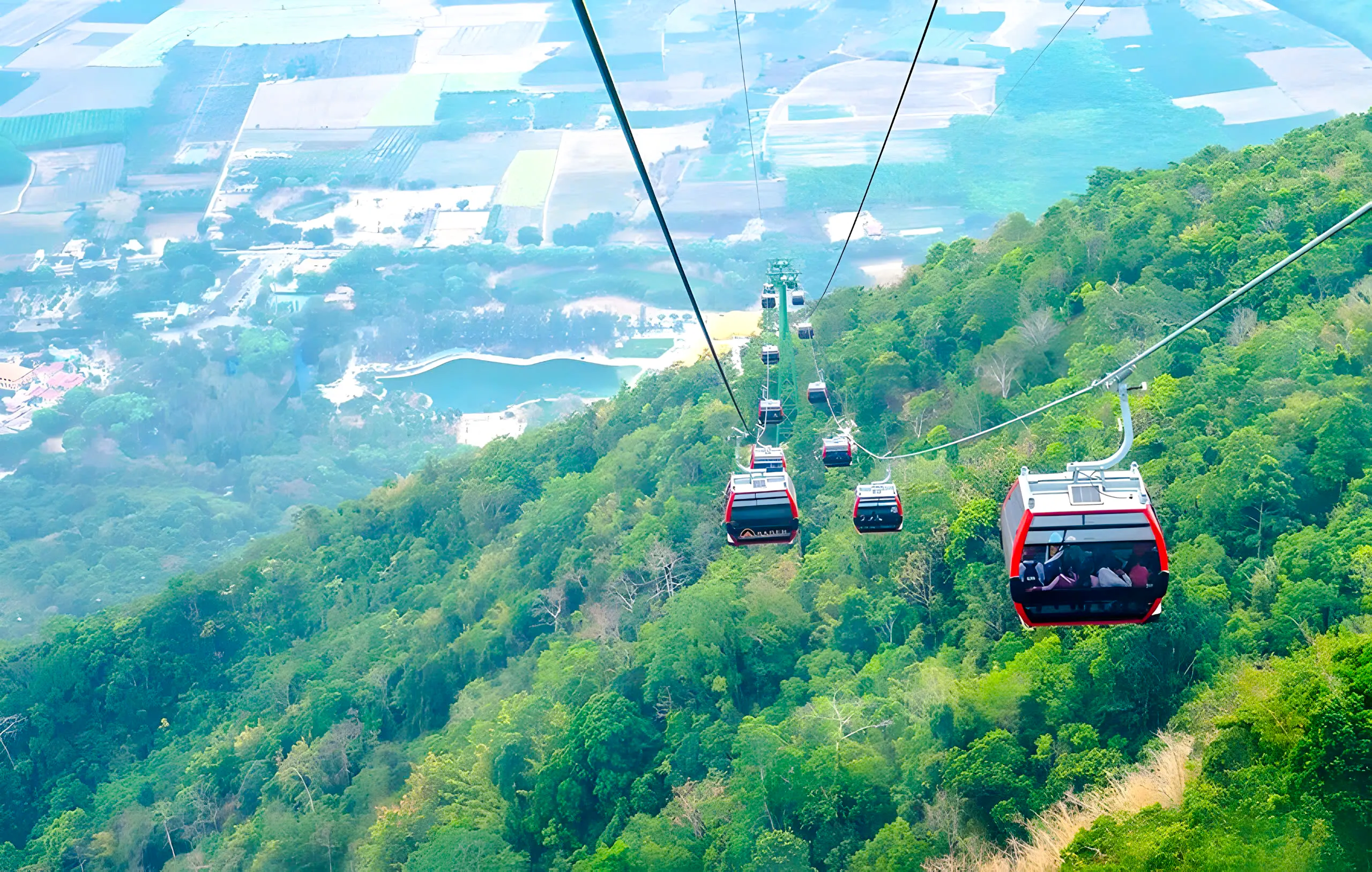 Cable cars ascending Black Virgin Mountain, Tay Ninh, with views of lush greenery and distant fields.