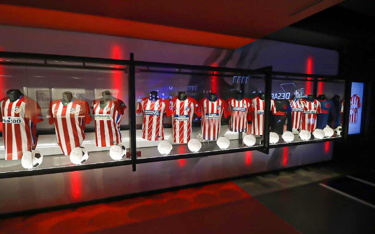 Atlético Madrid jerseys and soccer balls on display at Territorio Atleti, Cívitas Metropolitano tour.