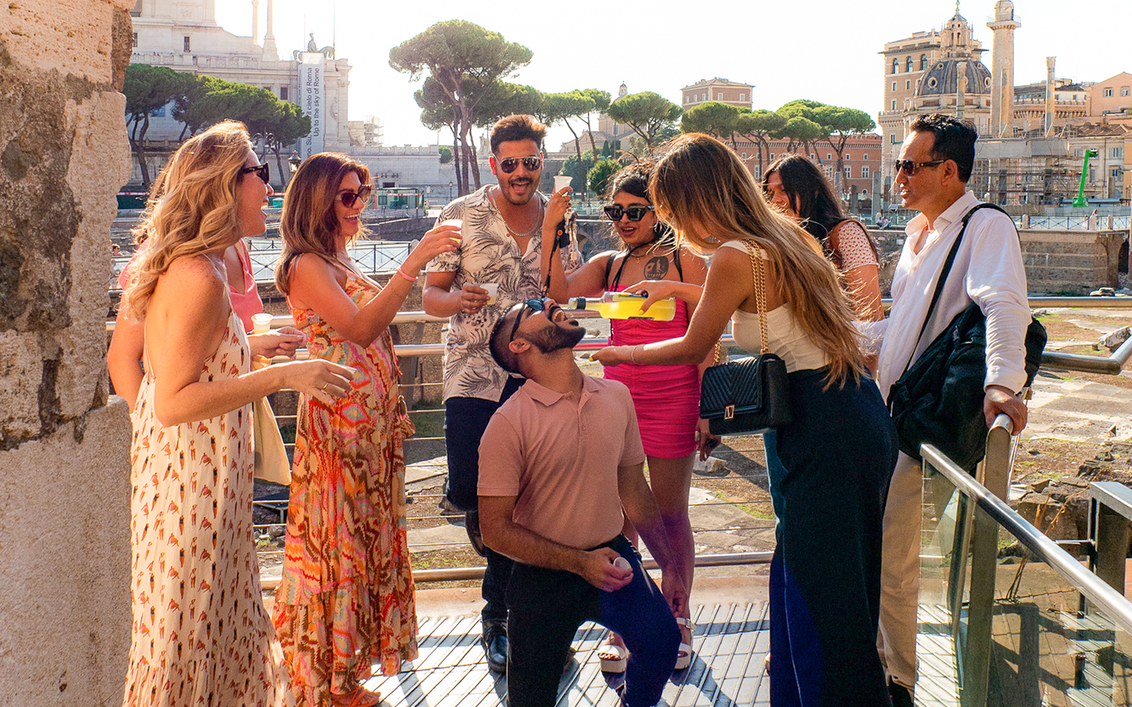 Tourists enjoying drinks together in Rome with historic buildings in the background.