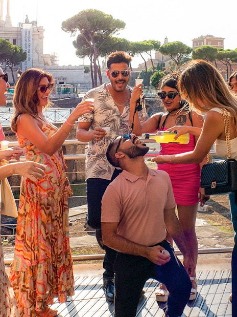 Tourists enjoying drinks together in Rome with historic buildings in the background.