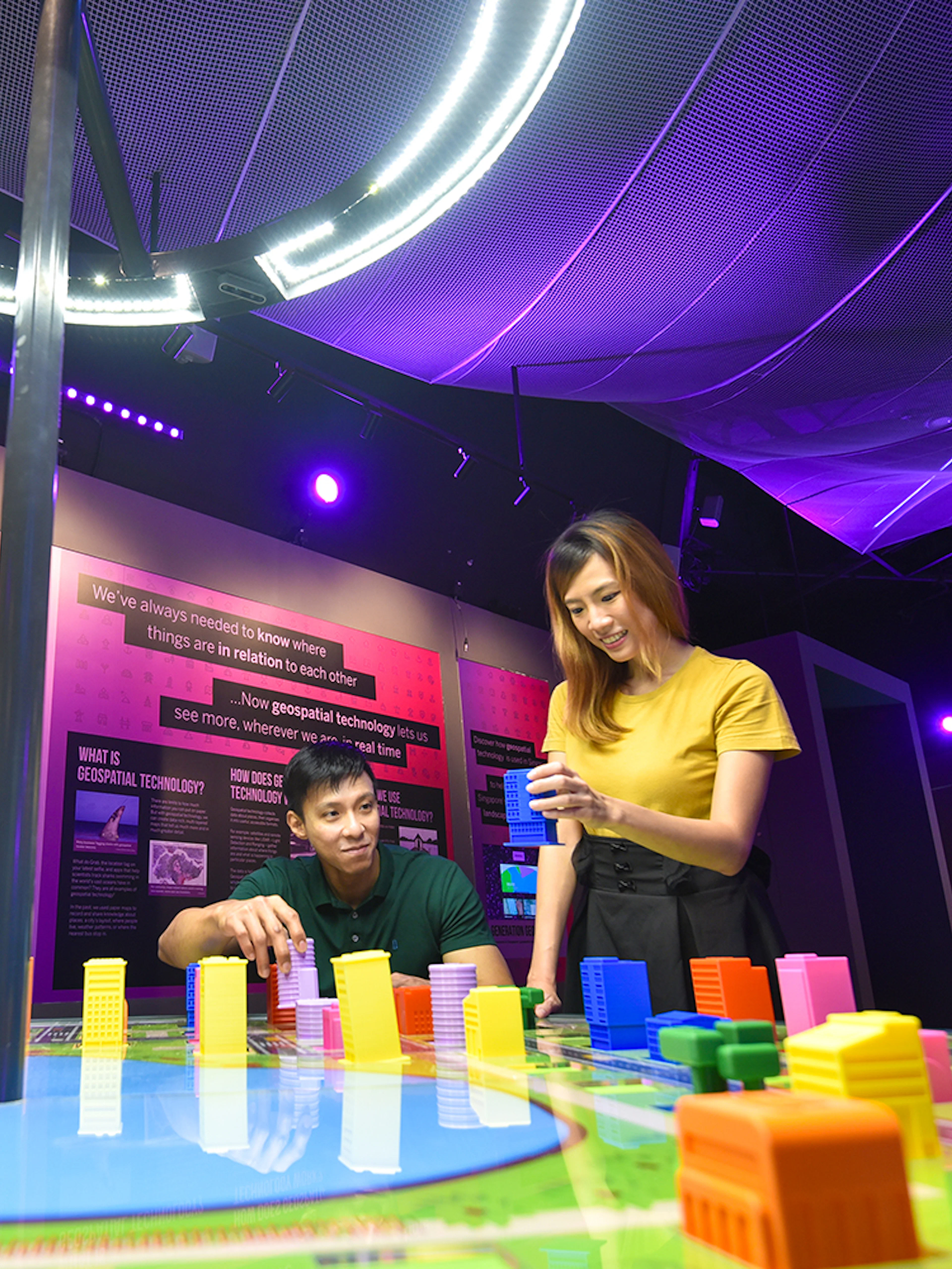 Visitors engaging with interactive geospatial technology exhibit at Science Centre Singapore.
