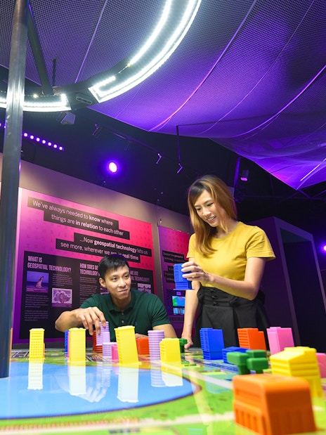 Visitors engaging with interactive geospatial technology exhibit at Science Centre Singapore.