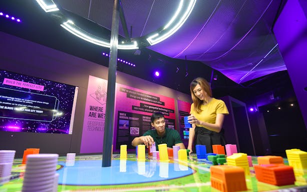 Visitors engaging with interactive geospatial technology exhibit at Science Centre Singapore.