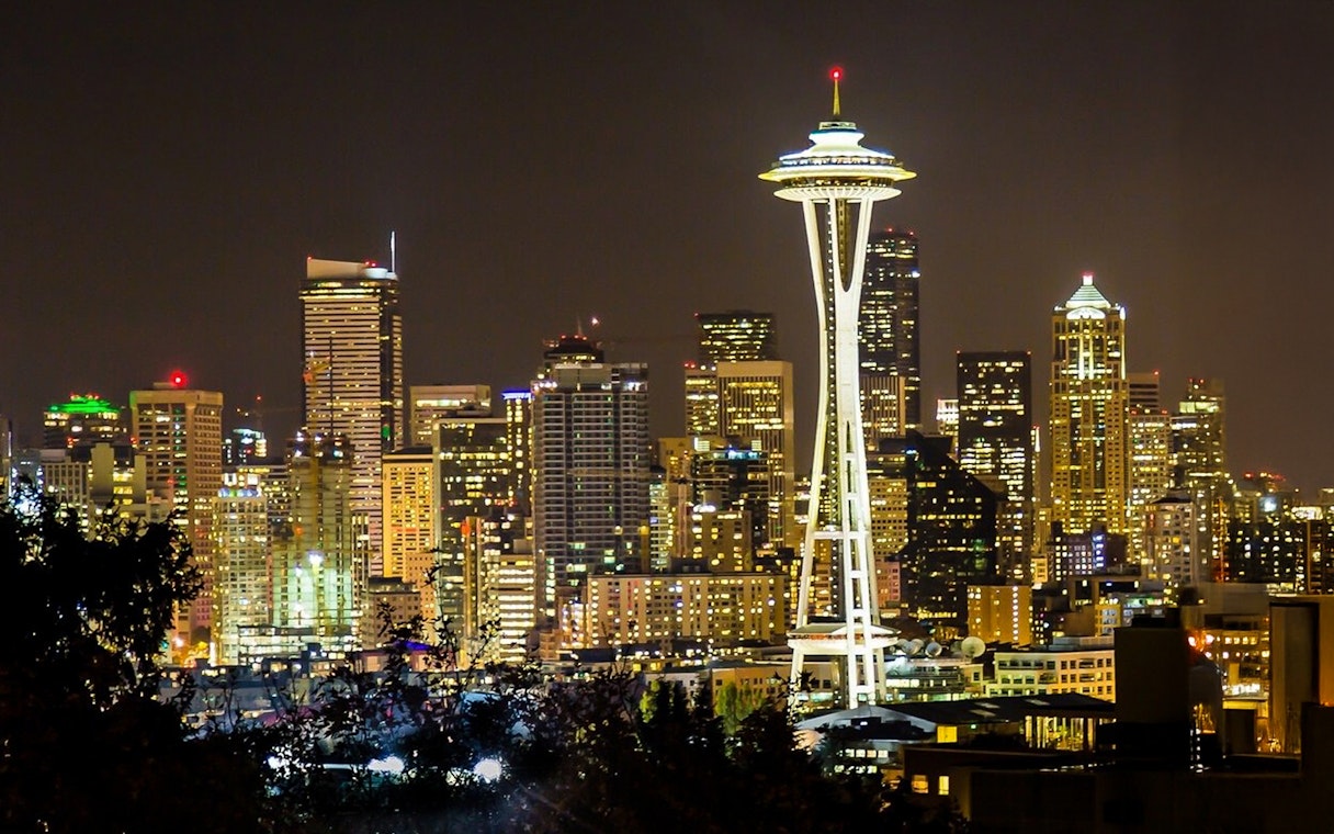 Seattle Space Needle illuminated at night with city skyline in the background.