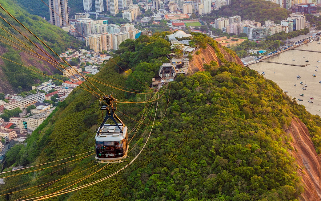 Tourists in Sugarloaf Mountain cable car viewing Rio de Janeiro cityscape.
