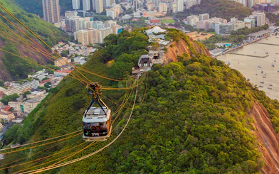 Tourists in Sugarloaf Mountain cable car viewing Rio de Janeiro cityscape.