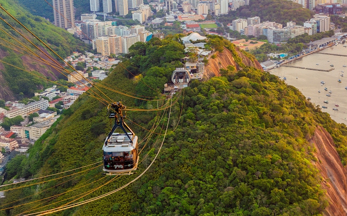 Tourists in Sugarloaf Mountain cable car viewing Rio de Janeiro cityscape.