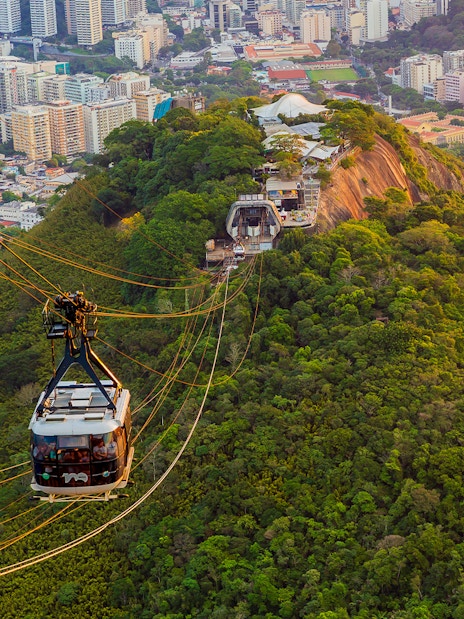 Tourists in Sugarloaf Mountain cable car viewing Rio de Janeiro cityscape.